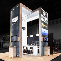 an exhibit booth with two televisions on the wall and tables in front of it