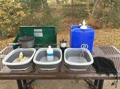 three buckets are sitting on top of a picnic table next to two coolers