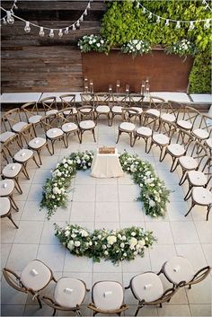 a circular arrangement of chairs and tables with flowers arranged in the shape of a heart