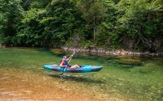 a man in a blue kayak paddles through clear water