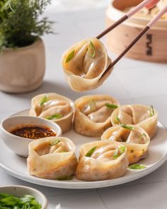 dumplings being served with dipping sauce on a plate