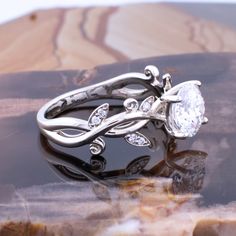 two wedding rings sitting on top of each other in front of a rock with water