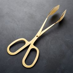 a pair of gold scissors sitting on top of a black table next to each other