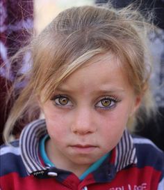 a close up of a child with blue eyes and blonde hair wearing a striped shirt