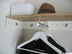 a hat is sitting on top of a coat hanger and some clothes are hanging from hooks