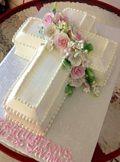 a cake decorated with flowers and the letter t on top of it is sitting on a table