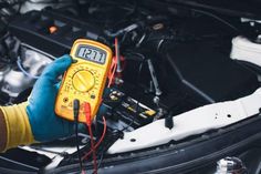 a person in blue gloves is checking the temperature on a car's engine bay