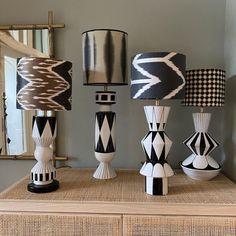 a collection of black and white lamps sitting on top of a dresser