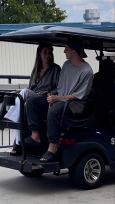 a man and woman sitting in the back of a golf cart