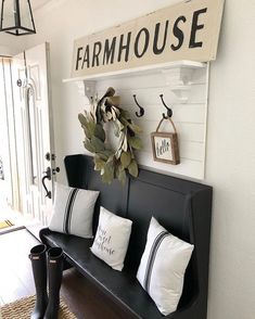 a black bench with white pillows on it and a sign above the bench that says farmhouse