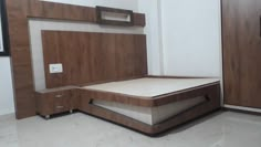 a bed with wooden headboard and drawers in a room