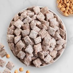 a white bowl filled with dog treats next to two bowls full of peanuts and almonds