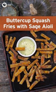 a tray filled with fried french fries next to a bowl of dip and some pumpkins