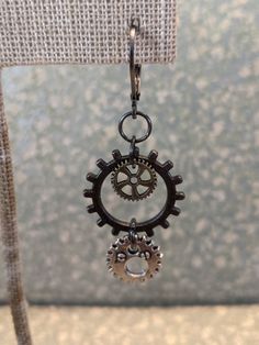 These steampunk earrings have multi color finishes. The large gear is gunmetal, the small gear inside is antique bronze and the lower gear is silver. Gear designs may differ but will be the same sizes. These simple steampunk earrings are perfect for that casual outfit that just needs an out-of-the-ordinary accessory to make it perfect! All metal is alloy and is lead-free and nickel-free. Jewelry purchased from Barnyard Steamworks comes with a Lifetime Guarantee. You will receive a polishing cloth to help you keep your item clean. A care and guarantee card will be included. Your item will come in a branded gift box and organza bag. Silver Steampunk Earrings, Nickel Free Metal Steampunk Earrings, Earrings Industrial, Gear Earrings, Industrial Earrings, Earrings Gothic, Steampunk Earrings, Steampunk Gears, Simple Earrings