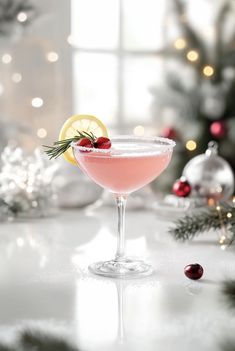 a pink cocktail in a coupe glass with a lemon slice and garnish