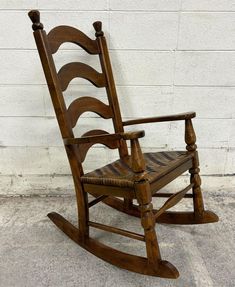 a wooden rocking chair against a white brick wall