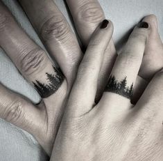 two fingers with trees tattooed on them, one is black and the other has white ink