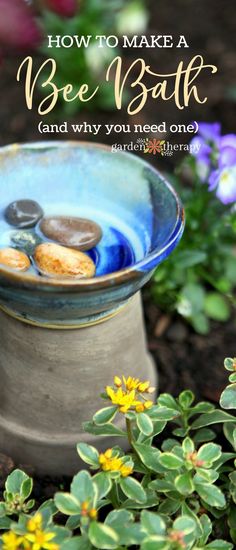 a bowl filled with rocks sitting on top of a flower bed next to plants and flowers