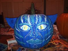 a blue pumpkin with an image of a cat's face painted on it