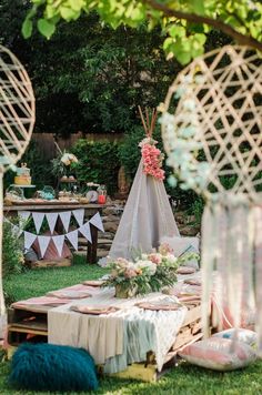 an outdoor party with tables, chairs and decorations on the grass in front of a teepee