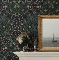 a painting and a mirror on a mantle in front of a wallpapered wall