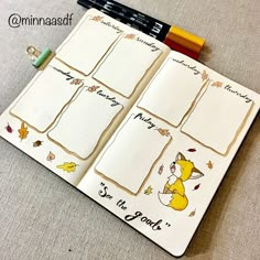 an open notebook with stickers on the pages and some pens in front of it