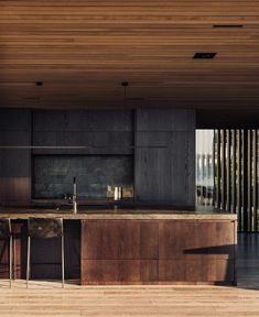 an open kitchen and dining area with wooden flooring on the outside wall, along with large sliding glass doors