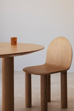 a wooden chair sitting next to a table with a cup on it