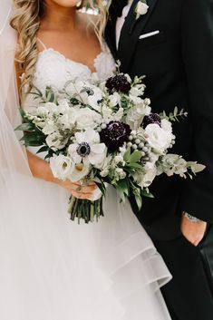 a bride and groom pose for a wedding photo in their tuxedo suit with the bride holding her bouquet