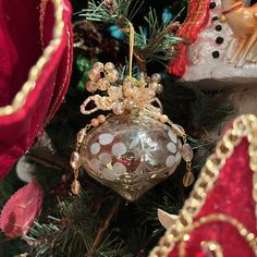 a christmas ornament hanging from the top of a tree with other ornaments around it