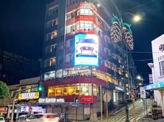 the building is lit up at night with lights on it's sides and cars driving down the street