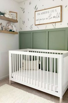 a white crib in a room with green paneling on the wall and shelves above it