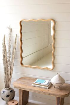 a wooden table with a mirror and vase on it