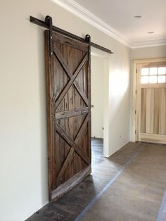 an open barn door in the middle of a room with hardwood floors and white walls