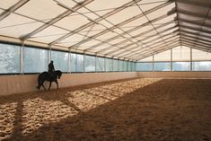 a man riding on the back of a brown horse in an enclosed area with lots of windows