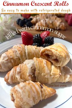 cinnamon crescent rolls on a white plate with berries and flowers in the background text reads, filled with cinnamon sugar so easy to make with refrigated dough