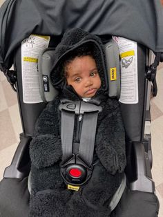 a small child in a car seat wearing a furry coat