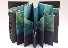 an open book with pages cut out to look like water and rocks on the inside