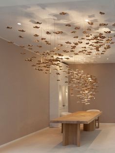 a room with a long wooden table and lots of gold butterflies hanging from the ceiling