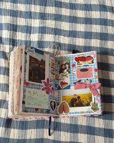 an open book with pictures on it sitting on a bed next to a blue and white checkered blanket