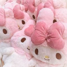 a pile of pink and white teddy bears with bows on their heads, all sitting side by side