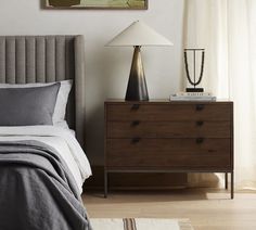 a bedroom scene with focus on the bed and nightstand, which has a painting hanging above it