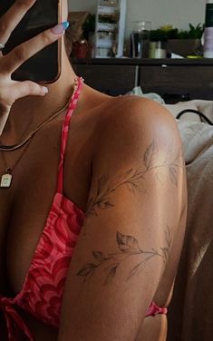 a woman with tattoos on her arm holding a cell phone in front of her face