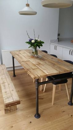 a wooden table sitting in the middle of a kitchen next to a bench and potted plant