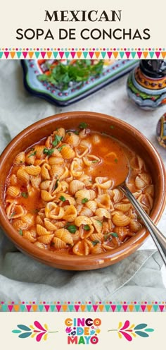 a bowl of mexican soup with pasta and garnishes in it on a table