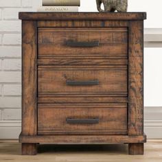 a wooden dresser with two books on top and a statue of a cat sitting on top