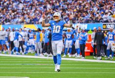 a football player is running on the field with his hands in the air and people watching