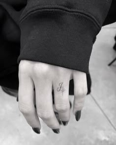 a person's hand with a small tattoo on the middle finger and an arrow in the middle