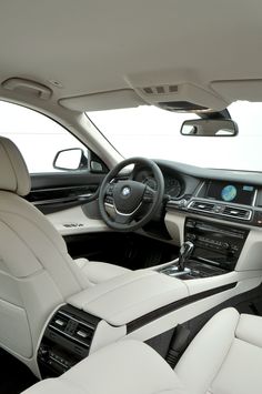 the interior of a car with all white leather and black trims, including steering wheel