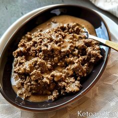 a bowl filled with meat and gravy on top of a table